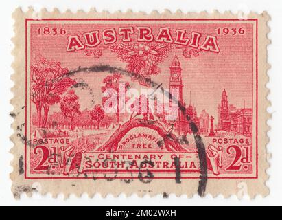 AUSTRALIA — 1936: Un francobollo rosso da 2 pence raffigurante l'albero del proclama e la vista di Adelaide. Centenario dell'Australia Meridionale. L'Old Gum Tree (conosciuto anche come The Prunproclama Tree) è un sito storico a Glenelg North, South Australia. Vicino a questo albero il 28 dicembre 1836, il governatore britannico John Hindmarsh ha rilasciato la proclamazione che annuncia l'istituzione del governo della colonia del Sud Australia. Una cerimonia si tiene ogni anno sul sito il giorno della proclamazione, con l'attuale Governatore che legge il discorso originale di Hindmarsh. L'albero stesso, probabilmente una gengiva rossa, era morto nel 1907 Foto Stock