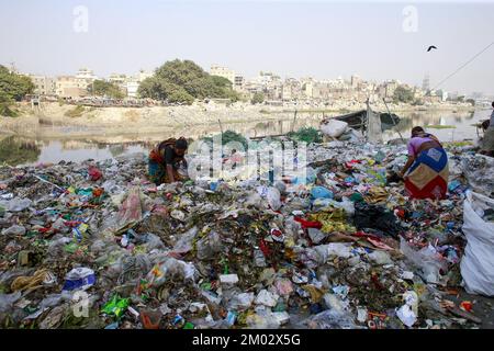 Dhaka, Bangladesh. 3rd Dec, 2022. Una donna del Bangladesh cerca un oggetto di plastica da una discarica di immondizia sulla riva del fiume Buriganga a Dhaka. I rifiuti chimici di mulini e fabbriche, i rifiuti domestici alla fine si fanno strada nel fiume Buriganga, che è considerato come la linea di vita di Dhaka. Migliaia di persone dipendono quotidianamente dal fiume per il bagno, il lavaggio dei vestiti, l'irrigazione dei cibi e il trasporto delle merci. Il fiume ha subito un'estrema perdita di biodiversità e ora è diventato nero. Credit: ZUMA Press, Inc./Alamy Live News Foto Stock