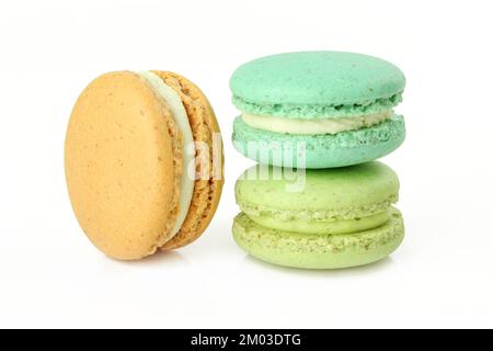 Tre macaroni di colore diverso isolati su sfondo bianco. Biscotti alla crema di delicatezza francesi Foto Stock