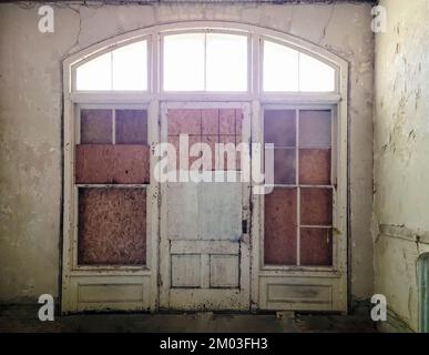 Abbandonato vecchia casa porta d'ingresso con tavole di legno e luce del sole nebulosa Foto Stock