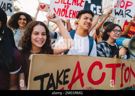 Gruppo di giovani attivisti felici che marciano per la pace e i diritti umani. Giovani multiculturali che protestano contro la guerra e la violenza. Dimostratore giovanile Foto Stock