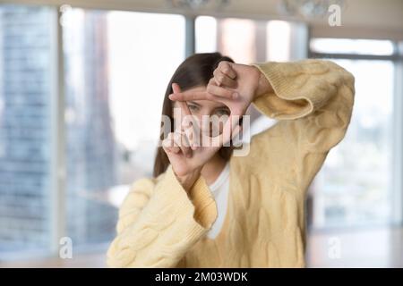 Bella ragazza giovane adulta indossando caldo maglione, facendo foto con le dita Foto Stock