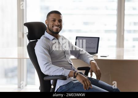 Felice uomo d'affari africano di successo in posa in ufficio Foto Stock