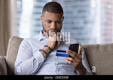 Premuroso utente africano carta di credito con cellulare Foto Stock