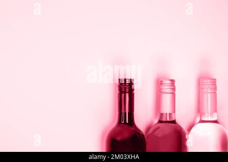 Colore dell'anno 2023 Viva Magenta. L'immagine con le bottiglie di vino rosso, rosa e bianco è tonata nel colore pantone di viva magenta. Nuovo colore moda. Vista dall'alto w Foto Stock