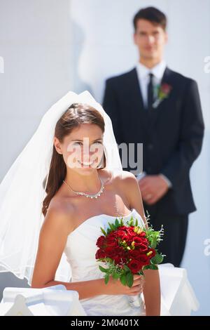 La ragazza dei suoi sogni. Una bella sposa sorridente mentre suo marito sta sullo sfondo. Foto Stock