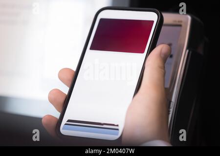 L'uomo effettua il pagamento utilizzando uno smartphone e un lettore di carte Foto Stock