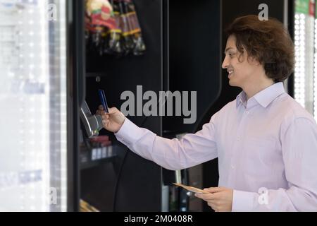 L'uomo effettua il pagamento per uno spuntino utilizzando il pagamento senza contanti Foto Stock