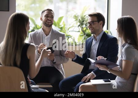 Quattro teammate professionali millennial risolvono il business riuniti in briefing Foto Stock