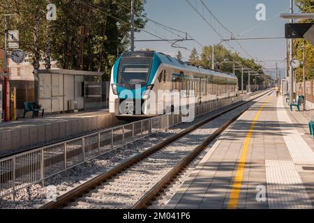 Un moderno treno passeggeri di colore blu e bianco entra nella stazione di Tivoli a Lubiana. Nuovo binario e stazione ferroviaria, atmosfera moderna. Foto Stock