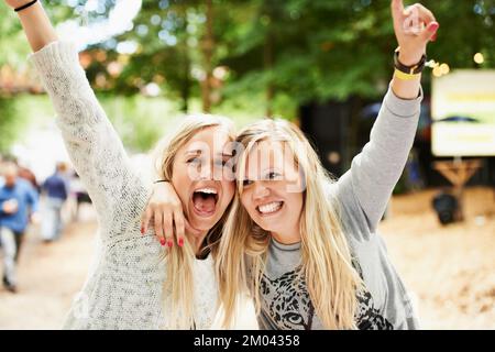 Lasciate che i tempi buoni rotolino. Ritratto di due giovani amici biondi che abbracciano e allietano mentre fuori ad un festival. Foto Stock