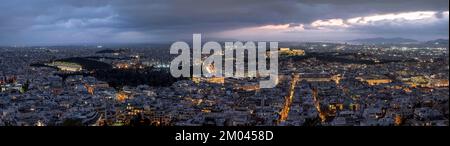 Panorama, vista sul mare delle case di Atene, tempio del Partenone illuminato sull'Acropoli, cielo nuvoloso drammatico, dal Monte Licabetto, Atene, Gr Foto Stock