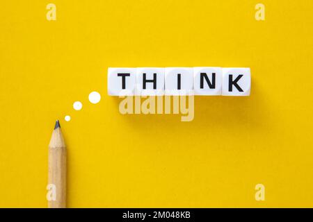 Matita con la parola Think su sfondo giallo. Pensare al concetto di idee creative. Foto Stock