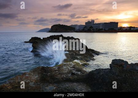 Santa Eulalia al tramonto con un'onda che si tuffa sulle rocce, Ibiza, Isole Baleari, Spagna. Foto Stock