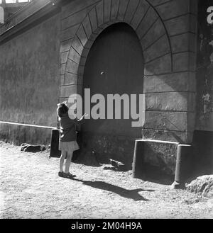 Attività estiva negli anni '1950s. Una giovane ragazza gioca da sola, lanciando una palla contro il muro. Un gioco tipico di dove la palla è stata gettata dodici volte contro il muro e ogni tiro è stato fatto in modo diverso. Se hai perso la palla o ha colpito il terreno, hai dovuto ricominciare. Fiskargatan 8 Stoccolma Svezia Kristoffersson Ref BC47-7 Foto Stock