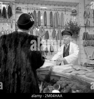 Shopping nel 1950s. Una donna ben vestita in una pelliccia cappotto e negozi di cappelli in un negozio di salumi Svezia 1950 Ref I1555 Foto Stock