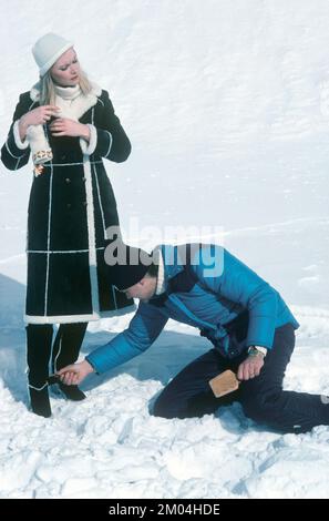 La moda negli anni '1980s. Un giovane modello è in fase di preparazione per una foto. Indossa la moda invernale degli anni, un cappotto caldo. Viene visualizzato un assistente che completa i dettagli. Svezia marzo 1980 Foto Stock
