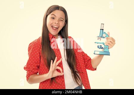 Lezione di bilogia di studio per bambini. Adolescente scuola ragazza con microscopio. Torna a scuola. Ragazza scienziata isolato su bianco. Ritratto di emotivo stupito eccitato Foto Stock