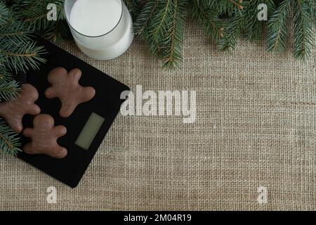 Biscotti di Natale su una scala e un bicchiere di latte per Babbo Natale. Concetto di dieta di stagione di festa. Composizione invernale stile di vita sano con spazio copia. Foto Stock