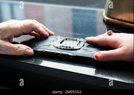 Tienen, Belgio - 11 11 2022 - mani di una donna anziana e di una donna di 40 yo con la sindrome di Down che tiene un telefono, Belgio Foto Stock