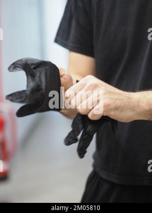 lo chef indossa guanti neri in una cucina professionale prima di cucinare filmati verticali Foto Stock