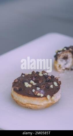 chef pasticcere che taglia ciambella scintillata al cioccolato per la decorazione delle torte sul tavolo della cucina Foto Stock