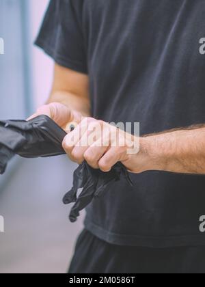 lo chef indossa guanti neri in una cucina professionale prima di cucinare filmati verticali Foto Stock