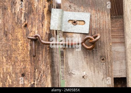 vecchio gancio arrugginito su un cancello di legno nel cortile Foto Stock