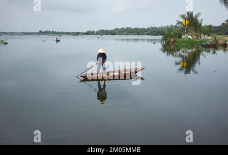 Uomo che attraversa il fiume in barca di legno a Hoi An Vietnam Foto Stock