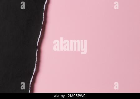 Pezzo di carta strappato con grunge nero con bordo sfilacciato su sfondo di carta color rosa pastello. Vista dall'alto, spazio di copia Foto Stock
