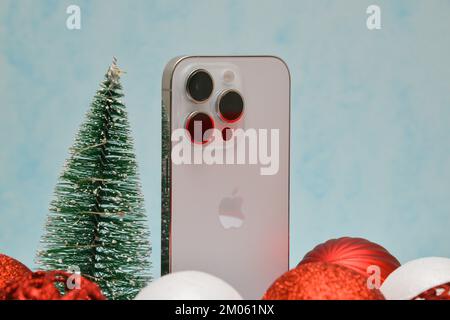 Riga/Lettonia - 4 dicembre 2022: Nuovo telefono moderno iPhone 14 pro tra le scintillanti decorazioni natalizie su sfondo nero. Regalo di Natale conce Foto Stock