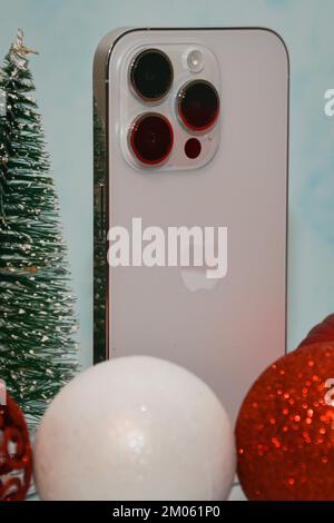 Riga/Lettonia - 4 dicembre 2022: Nuovo telefono moderno iPhone 14 pro tra le scintillanti decorazioni natalizie su sfondo nero. Regalo di Natale conce Foto Stock