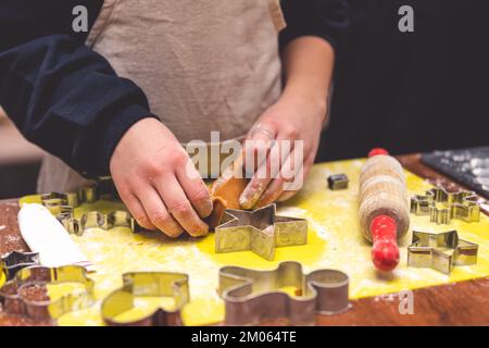 La ragazza fa i biscotti dello zenzero con le forme del biscotto di Natale. natale, capodanno fatto in casa Foto Stock