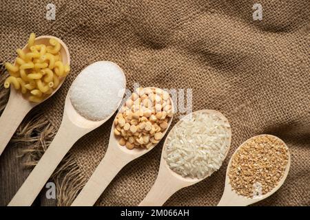 zucchero riso piselli pasta cereali su cucchiai di legno sul tavolo in cucina, cibo Foto Stock