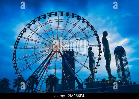 Batumi, Georgia - 17 dicembre 2021 - Time lapse of Moving Sculpture Ali and Nino di Tamar Kvetitadze con ruota ferris e torre alfabetica backgroun Foto Stock