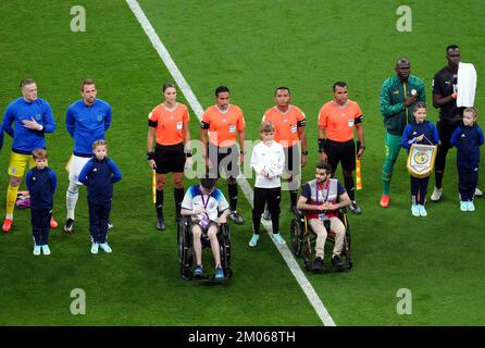 Ufficiali e mascotte si allineano insieme a Harry Kane, capitano d'Inghilterra, e Kalidou Koulibaly, senegalese, in vista della Coppa del mondo FIFA Round di sedici partite presso l'al-Bayt Stadium di al Khor, Qatar. Data immagine: Domenica 4 dicembre 2022. Foto Stock
