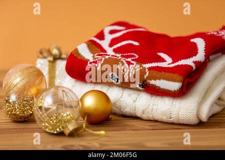 Caldi pullover natalizi. Inverno vacanza maglioni a maglia con motivo su uno sfondo di legno con Natale decorations.Stack di caldo Natale Foto Stock