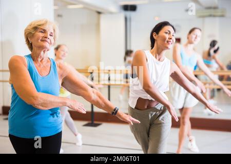 Ritratto di donna matura praticando danza balletto si muove durante la classe di gruppo in studio coreografico Foto Stock