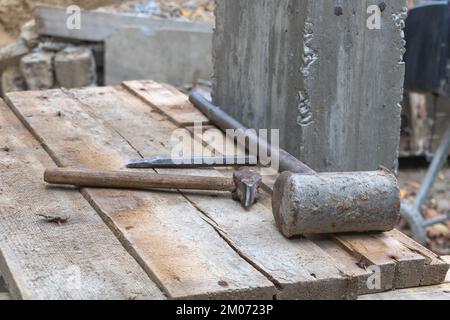 Uno scalpello e due martelli sul piano di lavoro nel cantiere - Construction Concept Foto Stock