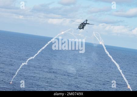 Un falco di nave HH-60 del 33rd Rescue Squadron spara razzi mentre conduce manovre evasive in un'area di addestramento designata sopra l'Oceano Pacifico, 22 novembre 2022. Il 33rd RQS si adopera per la mobilitazione, lo spiegamento e l'impiego di elicotteri e per il salvataggio di militari statunitensi e alleati e di personale civile. (STATI UNITI Foto Air Force di Senior Airman Cesar J. Navarro) Foto Stock