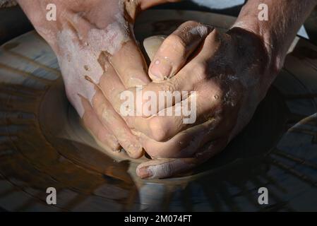 Un primo piano di due mani bagnate che formano un cono di argilla in una ciotola su una ruota di ceramica in una dimostrazione alla fiera d'arte di Tucson, Arizona Foto Stock