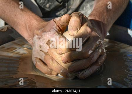 Un primo piano di due mani bagnate che formano un cono di argilla in una ciotola su una ruota di ceramica in una dimostrazione alla fiera d'arte di Tucson, Arizona Foto Stock