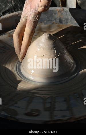 Primo piano di una mano bagnata che forma un cono di argilla in una ciotola su una ruota di ceramica in una dimostrazione alla fiera d'arte di Tucson, Arizona Foto Stock