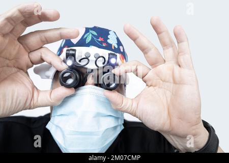 Dottore con lenti d'ingrandimento per chirurgia in un'azione ravvicinata o esaminando qualcosa in dettaglio Foto Stock