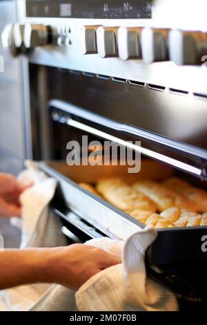 Niente come quell'odore di pane fresco. qualcuno che prende i prodotti appena sfornati da un forno. Foto Stock