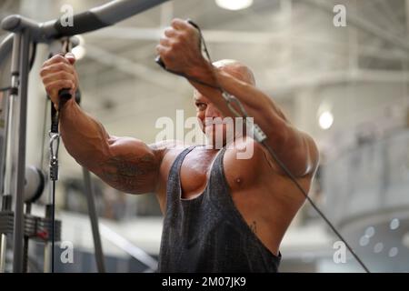 Mostra forza e determinazione. Un bodybuilder maschile che utilizza l'attrezzatura fisica per allenarsi in palestra. Foto Stock