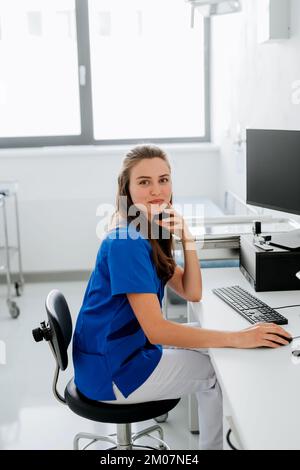 Giovane donna medico seduto alla scrivania dell'ufficio dell'ospedale. Foto Stock
