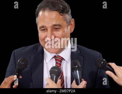 Fare una dichiarazione. Un uomo maturo in tuta che fa una conferenza stampa su uno sfondo nero. Foto Stock