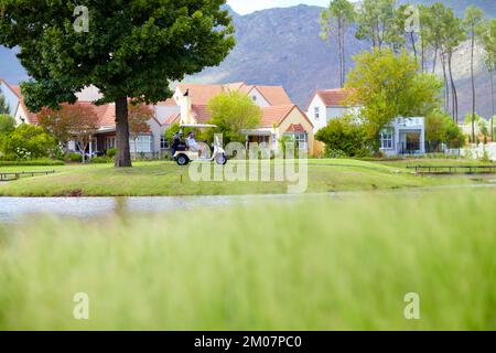 Pittoresco. Golfisti seduti in un golf cart sul campo di fronte al club house. Foto Stock