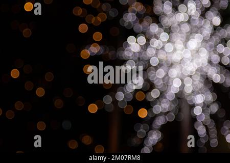 Luci bokeh dorate astratte gialle, arancioni isolate su sfondo nero con spazio copia. Concetto di stagione di Natale e di festa, risorse grafiche, gre Foto Stock